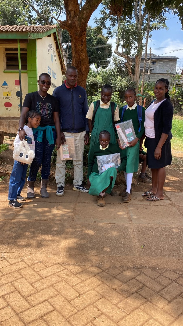 Adults and students gathered outside a school during a community visit.