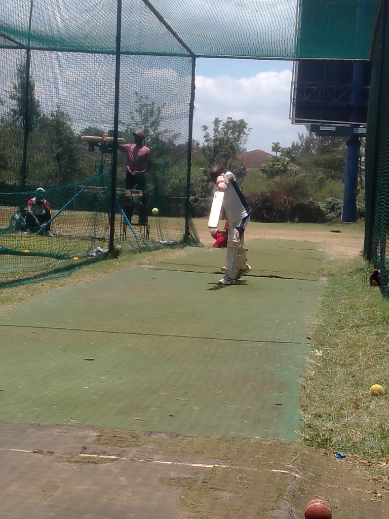 A player batting in the academy's outdoor practice nets.